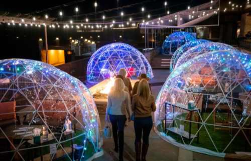 A cozy outdoor dining area with illuminated igloo-like structures and string lights, creating a festive atmosphere.