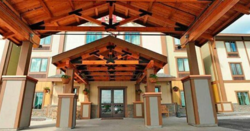 A welcoming hotel entrance with a wooden canopy, stone accents, and large glass doors.