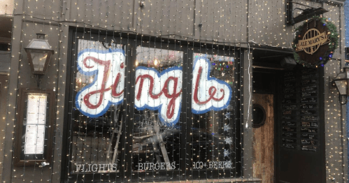 A festive restaurant window displays the word "Jingle" with lights, featuring a menu of flights, burgers, and beer.