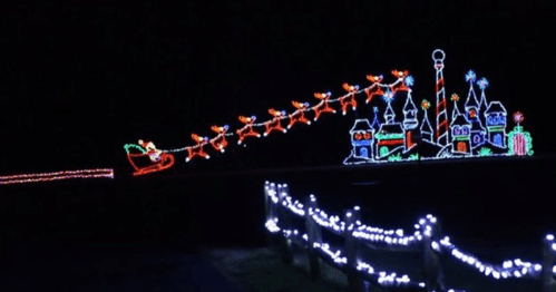 Colorful holiday lights depict Santa's sleigh with reindeer flying over a whimsical castle and candy cane.