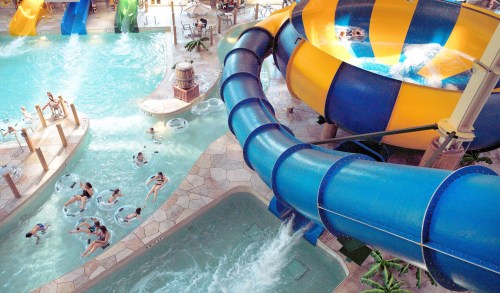 A vibrant indoor water park featuring slides, a lazy river, and children enjoying the water.