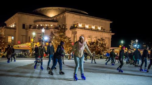 A lively ice skating rink at night, with people skating and festive lights illuminating the scene.