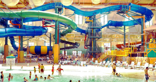Indoor water park featuring colorful water slides, a wave pool, and families enjoying the attractions.