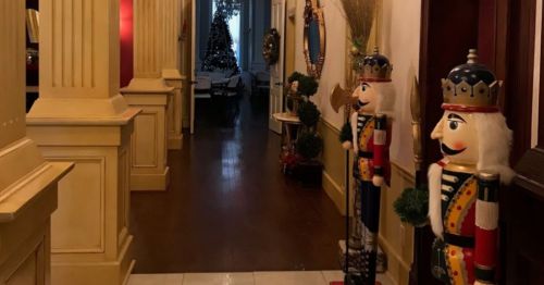 A festive hallway with nutcracker decorations and a Christmas tree in the background.