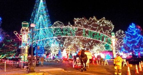 Colorful holiday lights illuminate a festive scene with a large tree and a sign reading "Holiday Lights."
