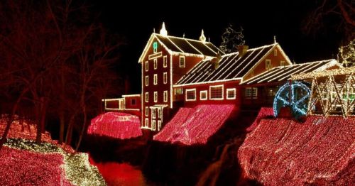 A beautifully lit house and surrounding landscape adorned with colorful holiday lights at night.