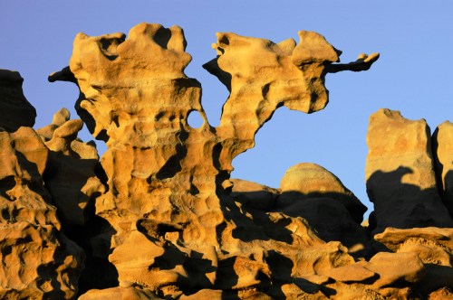 Unique rock formations with intricate shapes and textures against a clear blue sky.