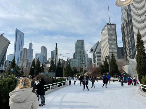 A bustling ice skating rink in a city park, surrounded by skyscrapers and trees under a cloudy sky.