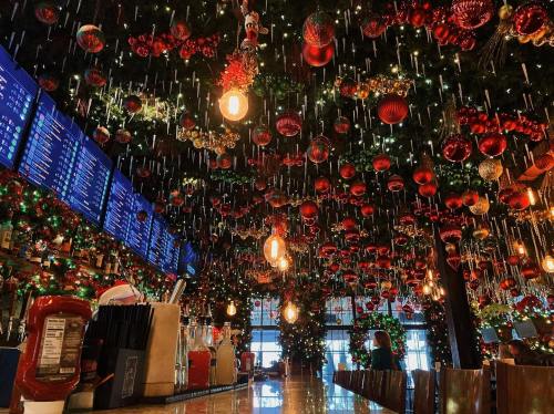 A festive bar decorated with hanging red and gold ornaments, twinkling lights, and Christmas trees.