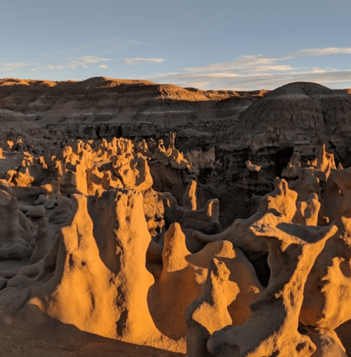 Rock formations illuminated by golden sunlight, creating a surreal landscape with unique shapes and textures.