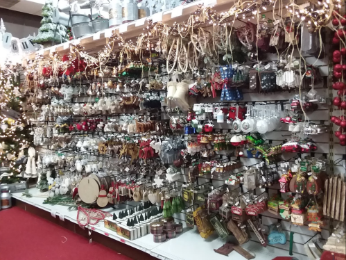 A festive display of various Christmas ornaments and decorations on a store wall, adorned with lights and greenery.