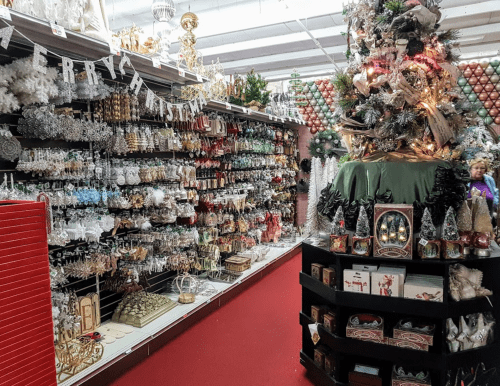 A festive store aisle filled with Christmas decorations, ornaments, and a decorated tree in the center.