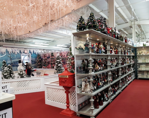 A festive store display with Christmas decorations, including trees, snowmen, and a red mailbox, set on a red carpet.