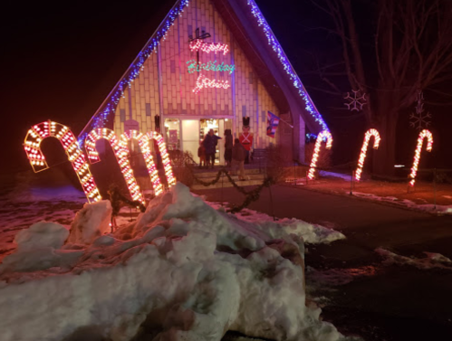 A festive building decorated with colorful lights and candy cane displays, surrounded by snow at night.