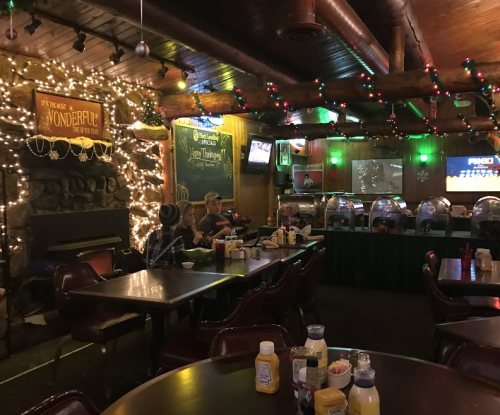 Cozy restaurant interior decorated with lights, featuring tables, a buffet, and patrons enjoying their meals.