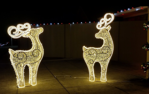 Two illuminated reindeer decorations with swirling designs, set against a dark background, surrounded by festive lights.