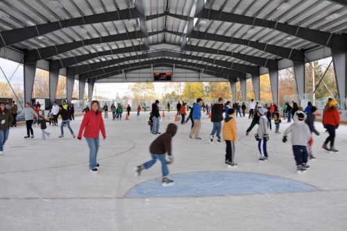 A busy indoor ice skating rink with people of all ages skating and enjoying the activity.