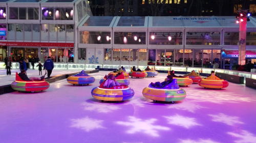 Colorful inflatable tubes on an ice rink, with people enjoying a fun winter activity under festive lights.