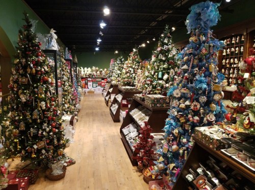 A festive store aisle filled with decorated Christmas trees and holiday ornaments, creating a cheerful atmosphere.