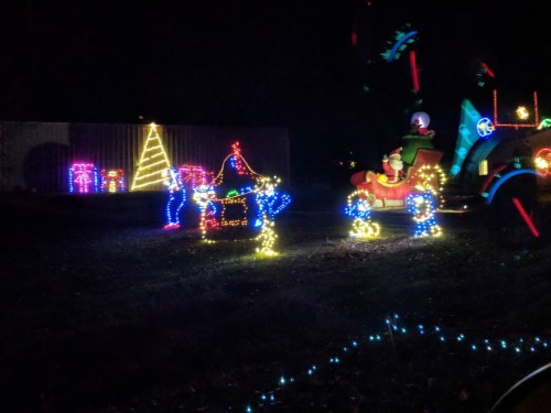Colorful holiday lights display featuring a Christmas tree, gifts, and a sleigh with Santa in a nighttime setting.