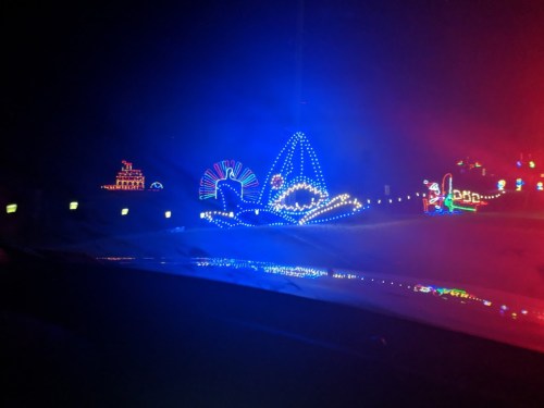 Colorful holiday lights illuminate a dark scene, featuring various festive shapes and designs.