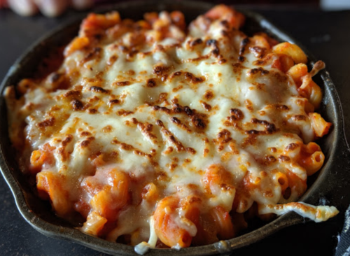 A baked pasta dish with melted cheese, golden brown on top, served in a cast iron skillet.