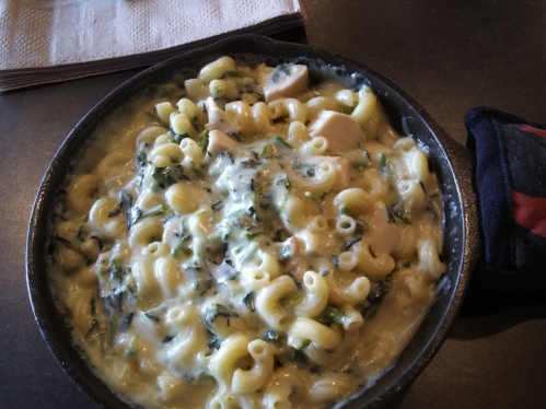 A bowl of creamy pasta with chicken and spinach, featuring curly macaroni in a rich sauce.