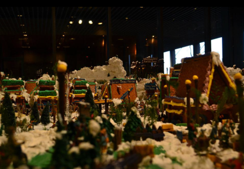 A festive display of gingerbread houses surrounded by snow and trees, creating a whimsical winter scene.
