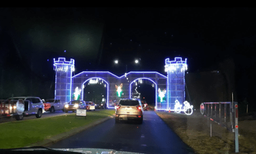 A brightly lit archway with festive decorations, cars lined up at night, creating a cheerful holiday atmosphere.