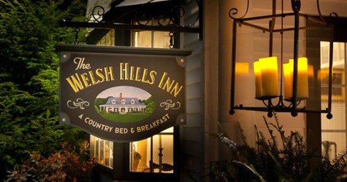 Sign for The Welsh Hills Inn, a country bed and breakfast, illuminated by warm candlelight at night.