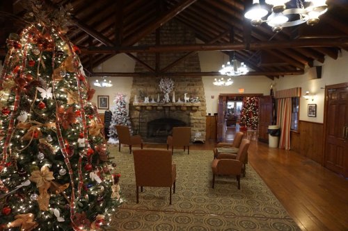 Cozy lodge interior decorated for the holidays, featuring a Christmas tree, fireplace, and festive lighting.