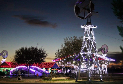 A festive scene at night featuring colorful holiday lights on buildings and a decorated windmill.