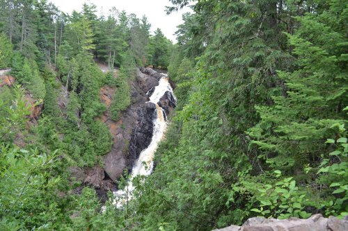 A waterfall cascading down rocky cliffs, surrounded by lush green trees and foliage.
