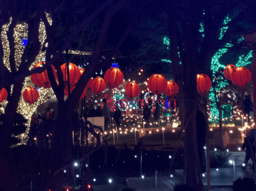 Colorful lanterns and festive lights illuminate a night scene, creating a vibrant holiday atmosphere.