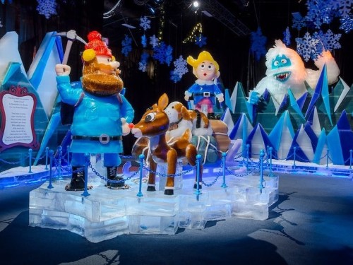 Colorful ice sculptures of characters from a holiday story, including a man with an axe, a reindeer, and a yeti.