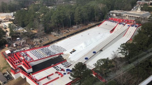 A large outdoor snow tubing hill with multiple lanes, surrounded by trees and spectators in the background.