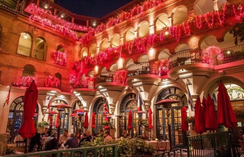 A beautifully lit courtyard restaurant with red decorations and outdoor seating, creating a warm evening atmosphere.