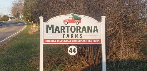 Sign for Martorana Farms featuring a red truck with a Christmas tree, promoting holiday displays and a Christmas tree farm.