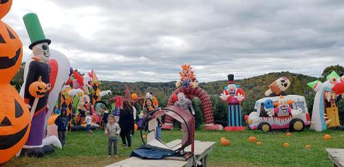 A festive outdoor scene with various inflatable Halloween decorations and people enjoying the atmosphere.
