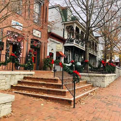 A charming street scene with festive decorations, including wreaths and ribbons, along brick buildings and stairs.