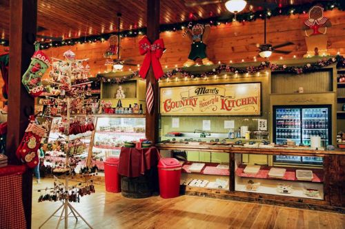 A cozy country kitchen decorated for the holidays, featuring festive lights, wreaths, and a display of baked goods.