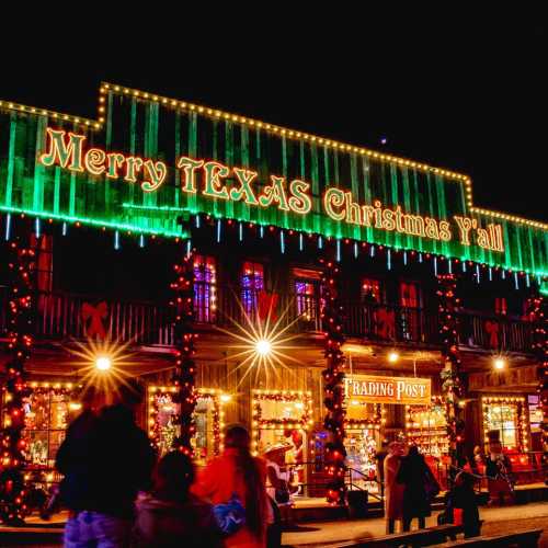 A festive building decorated with colorful Christmas lights, featuring "Merry TEXAS Christmas Y'all" in bright green.