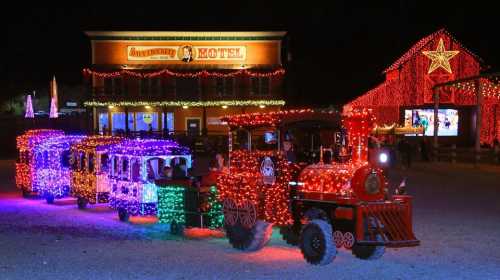 A brightly lit train decorated with colorful lights in front of a hotel, set against a night sky.