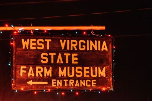 Sign for the West Virginia State Farm Museum, illuminated with festive lights, indicating the entrance.