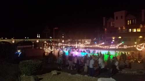 A lively night scene with people skating on an ice rink, surrounded by colorful lights and festive decorations.