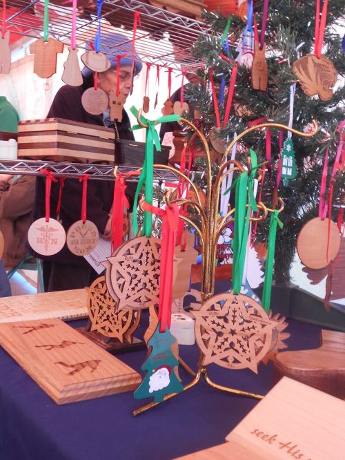 A display of wooden ornaments and decorations hanging from a stand at a craft market.