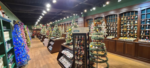 A festive store aisle filled with decorated Christmas trees and holiday ornaments on display.