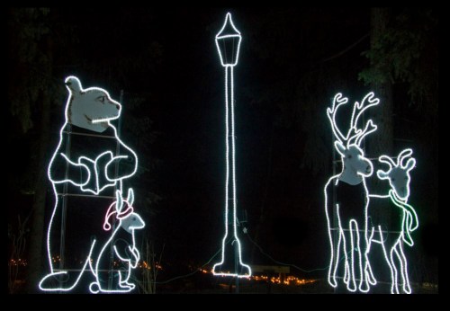 Colorful holiday lights depicting a bear, a rabbit, and two reindeer near a lamppost at night.