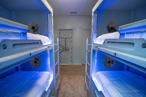 A modern dormitory with blue-lit bunk beds and a secure door, creating a futuristic sleeping space.