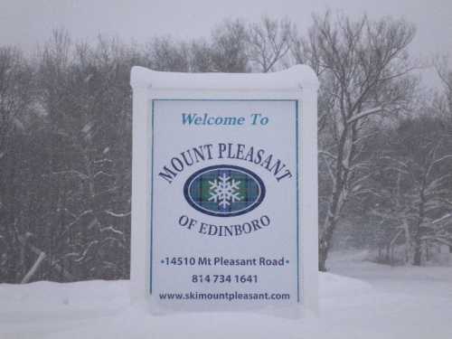 Sign welcoming visitors to Mount Pleasant of Edinboro, surrounded by snow-covered landscape.